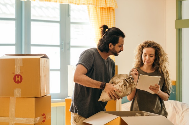 a man and a woman packing their things with the help of a list